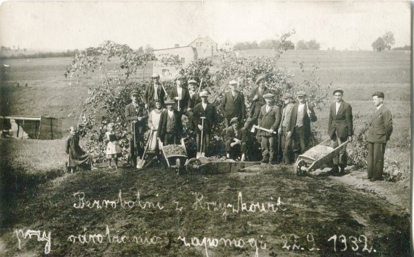 Fotografia przedstawia grupę mężczyzn z narzędziami - łopatami, taczkami kilofami